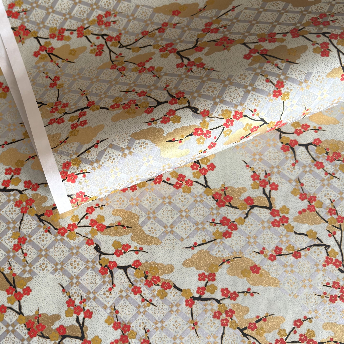japanese silk-screen handmade paper, chiyogami, showing branches of red cherry blossom and gold clouds on a backdrop of silver, cream and gold