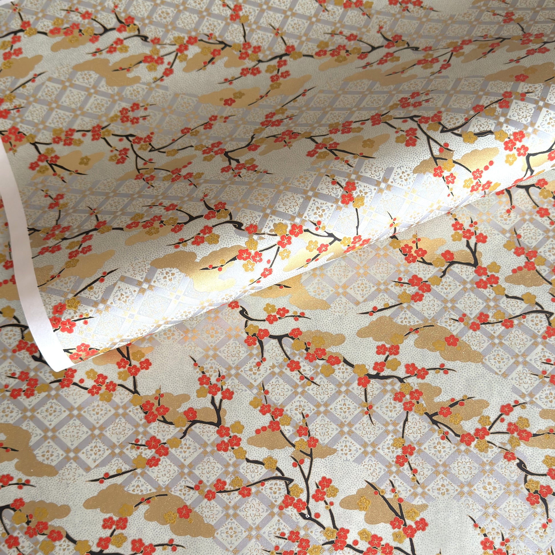japanese silk-screen handmade paper, chiyogami, showing branches of red cherry blossom and gold clouds on a backdrop of silver, cream and gold