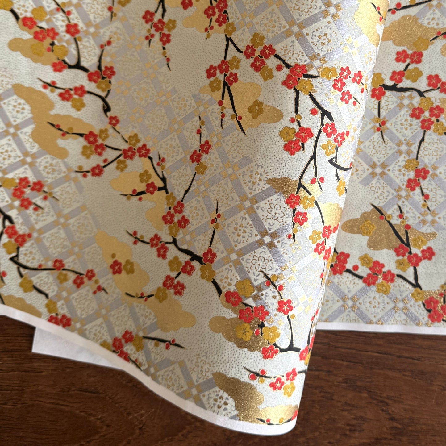 japanese silk-screen handmade paper, chiyogami, showing branches of red cherry blossom and gold clouds on a backdrop of silver, cream and gold