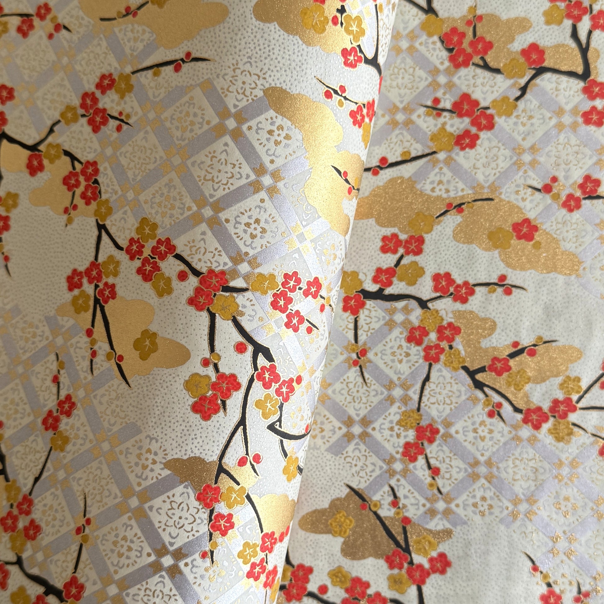 japanese silk-screen handmade paper, chiyogami, showing branches of red cherry blossom and gold clouds on a backdrop of silver, cream and gold