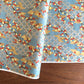 japanese silk-screen handmade paper showing branches of red blossom, gold clouds on a teal, gold and silver geometric backdrop.