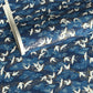 a sheet of Japanese chiyogami yuzen paper with a traditional pattern of white cranes flying with a deep blue background of patterned clouds
