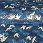 a sheet of Japanese chiyogami yuzen paper with a traditional pattern of white cranes flying with a deep blue background of patterned clouds