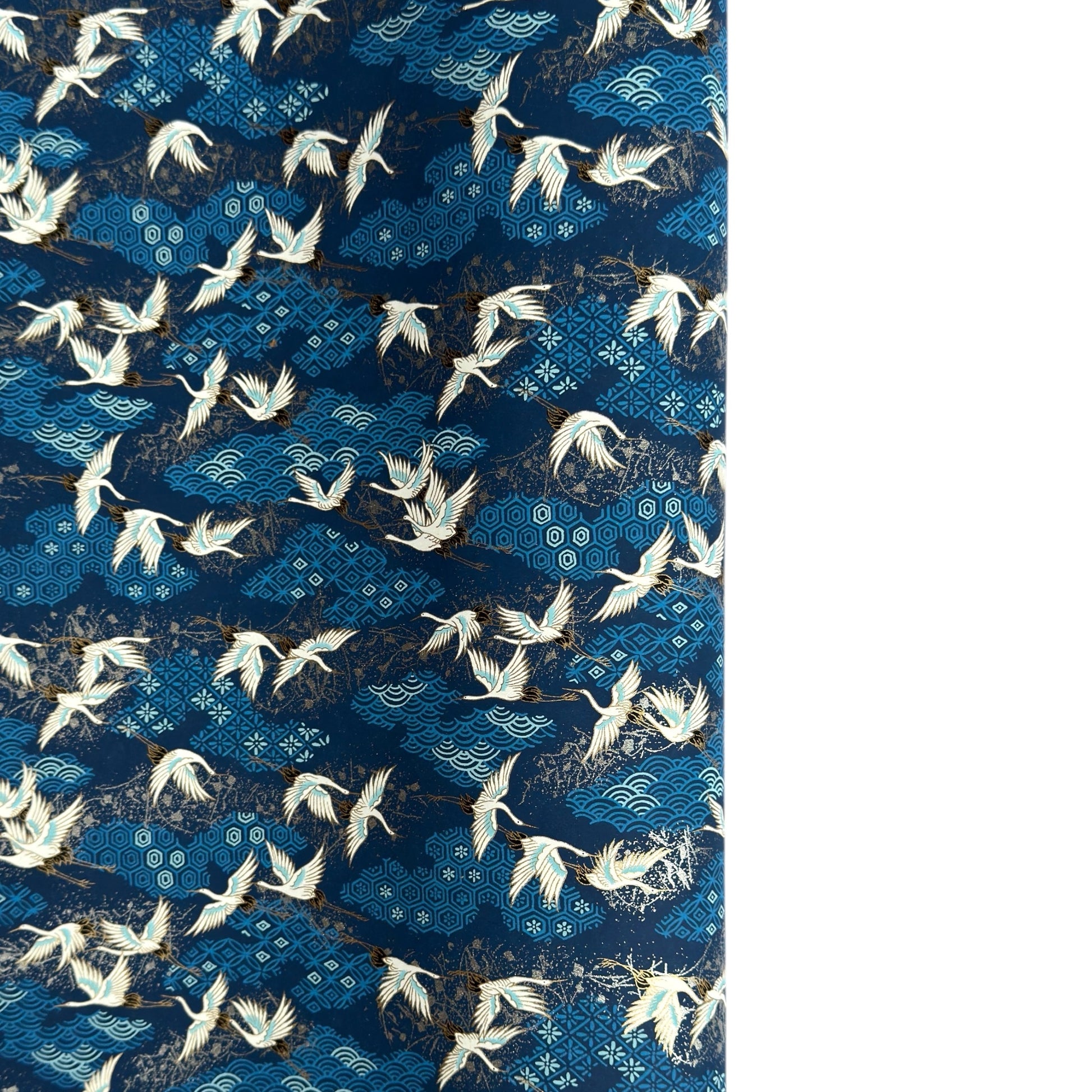 a sheet of Japanese chiyogami yuzen paper with a traditional pattern of white cranes flying with a deep blue background of patterned clouds