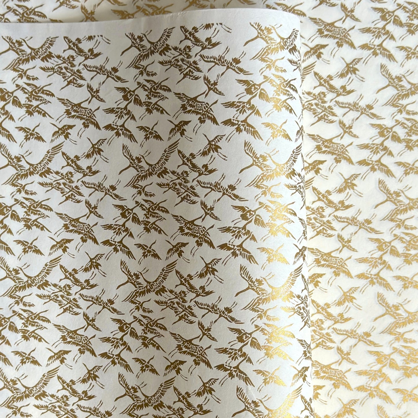 japanese silk-screen handmade paper showing gold cranes in flight on ivory backdrop