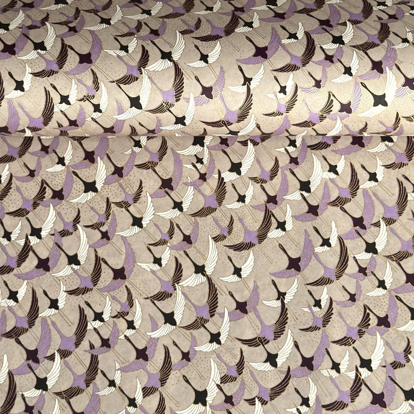 a sheet of Japanese chiyogami yuzen paper with a pattern of cranes in flight in lilac, black, taupe and gold