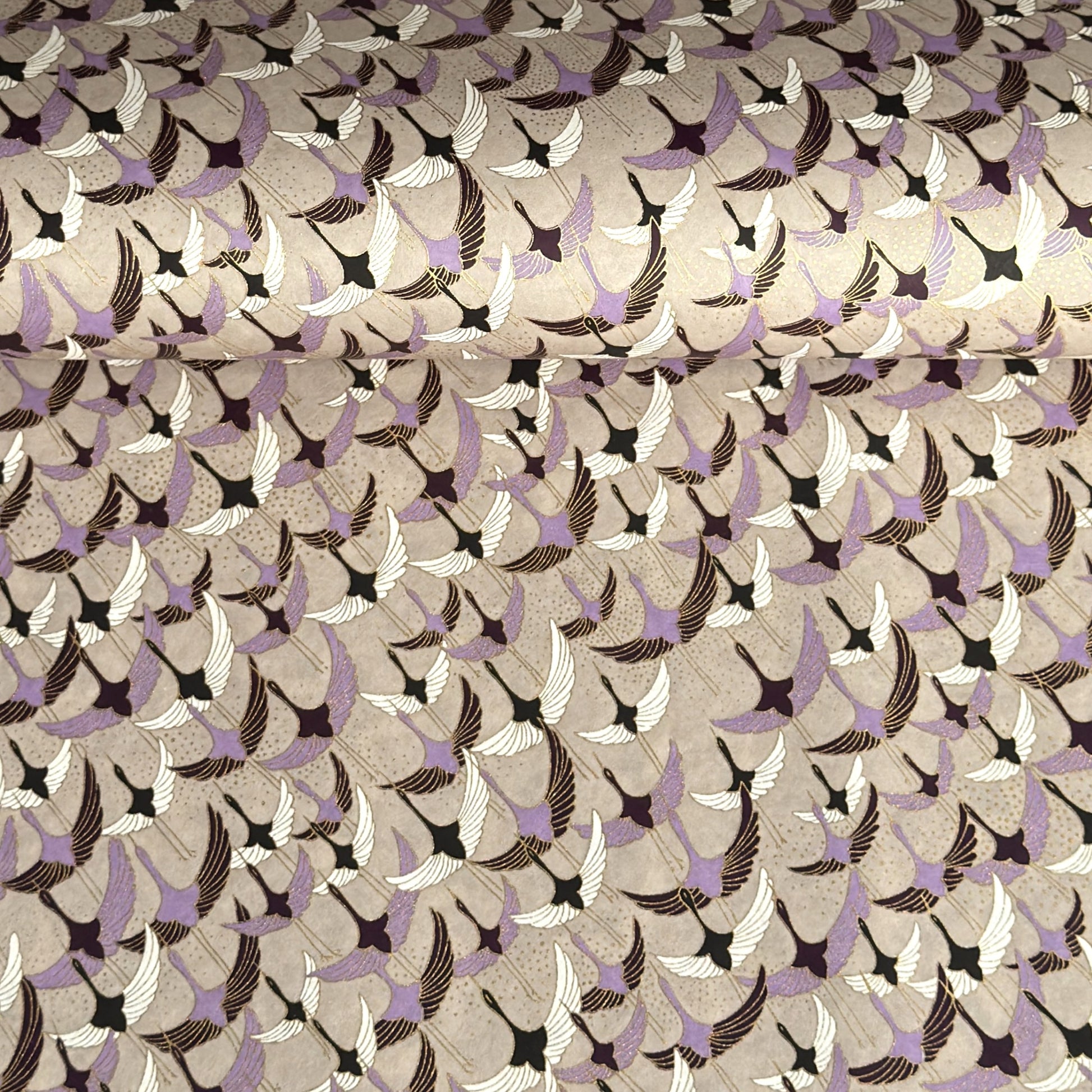 a sheet of Japanese chiyogami yuzen paper with a pattern of cranes in flight in lilac, black, taupe and gold