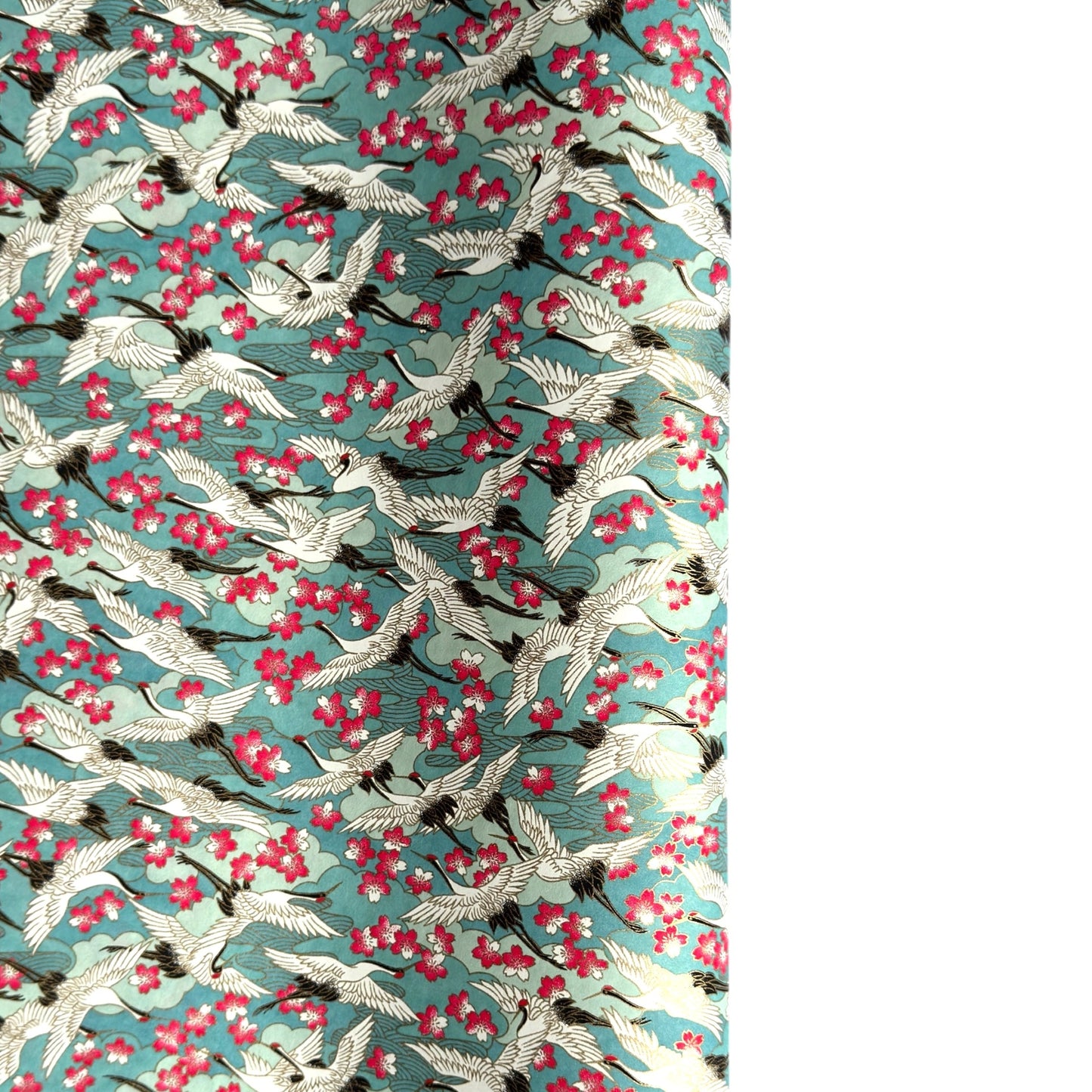 Japanese chiyogami paper with a pattern of white cranes, pink cherry blossom on a blue background. 