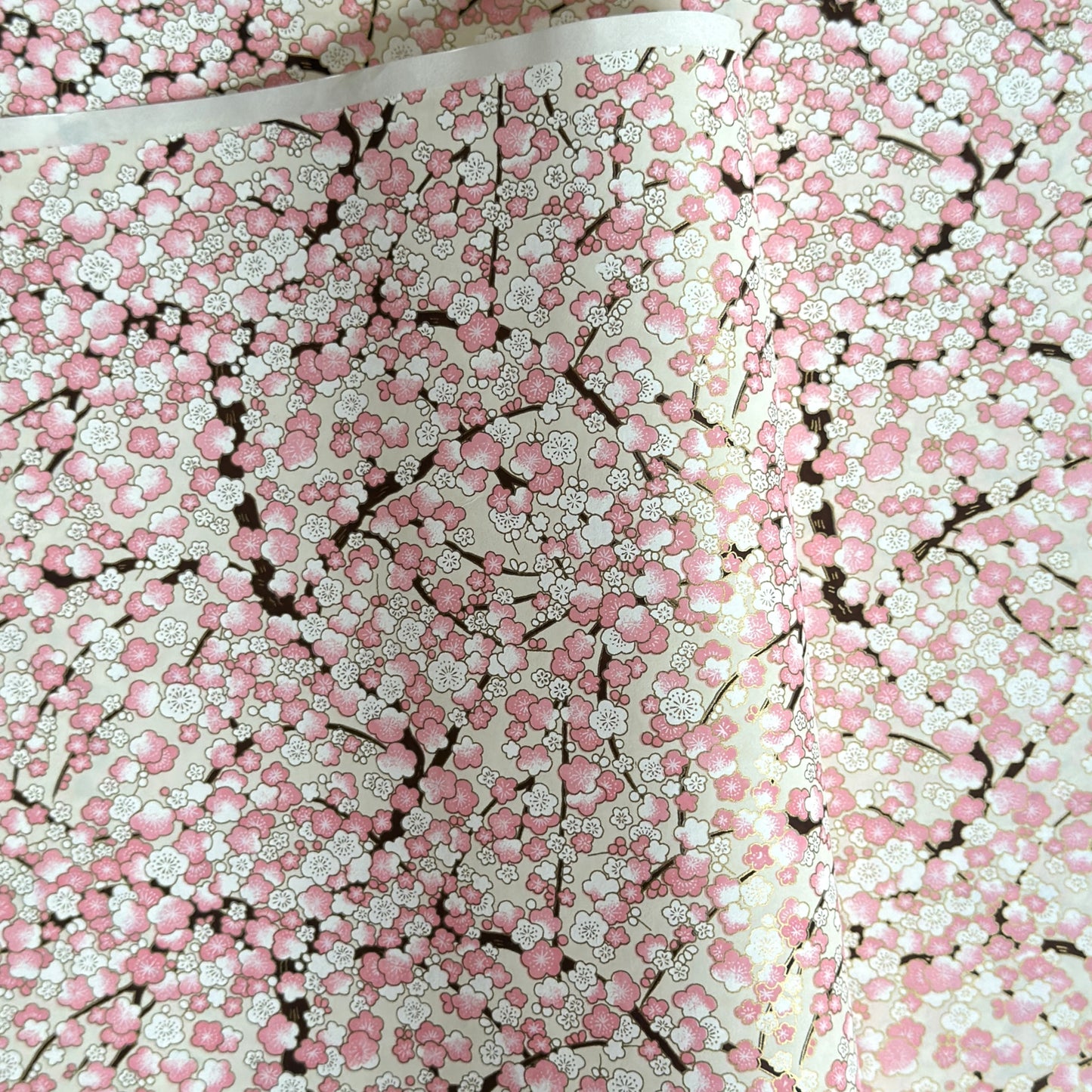 Japanese chiyogami paper with pale pink plum blossom, dark brown branches on an ivory background.