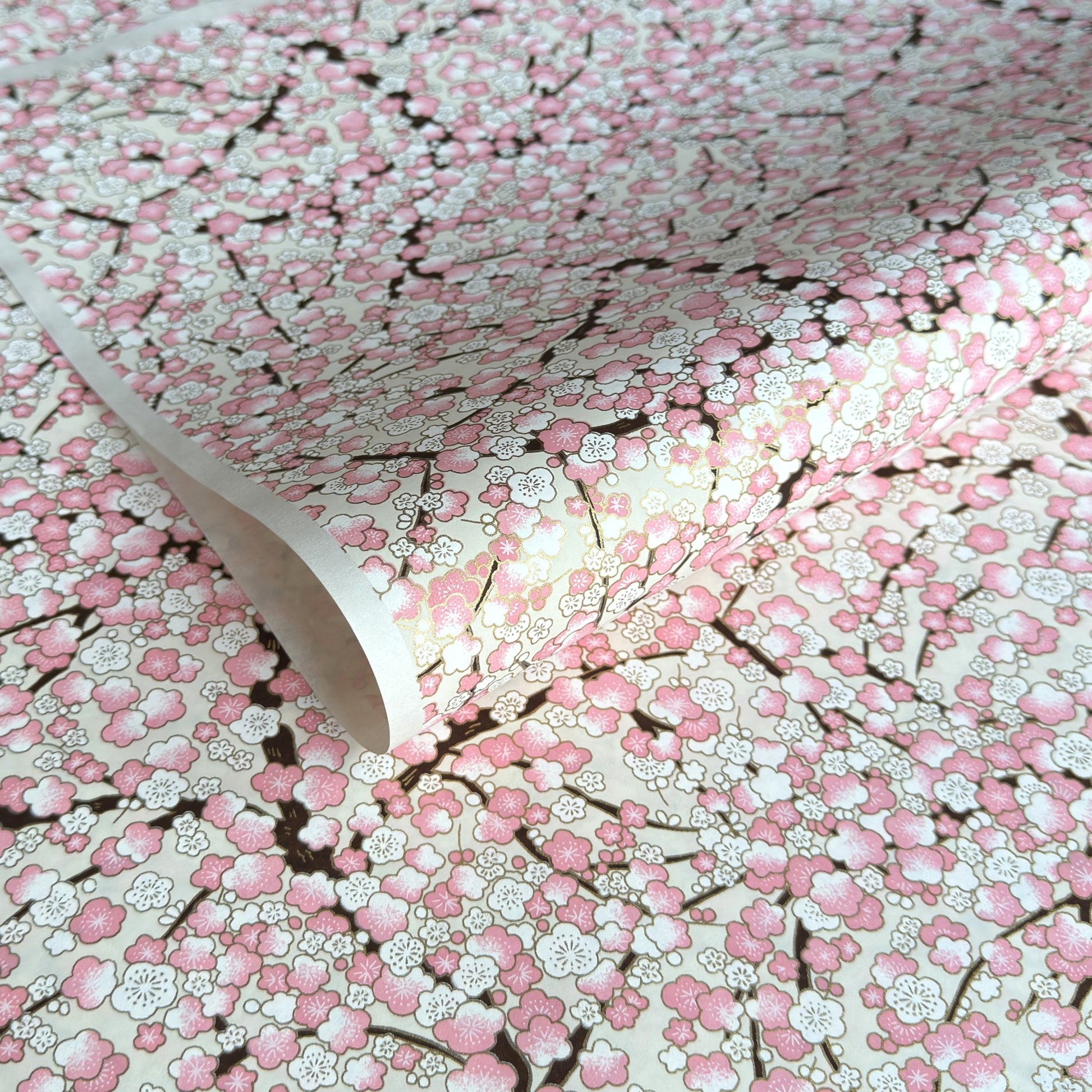 Japanese chiyogami paper with pale pink plum blossom, dark brown branches on an ivory background.