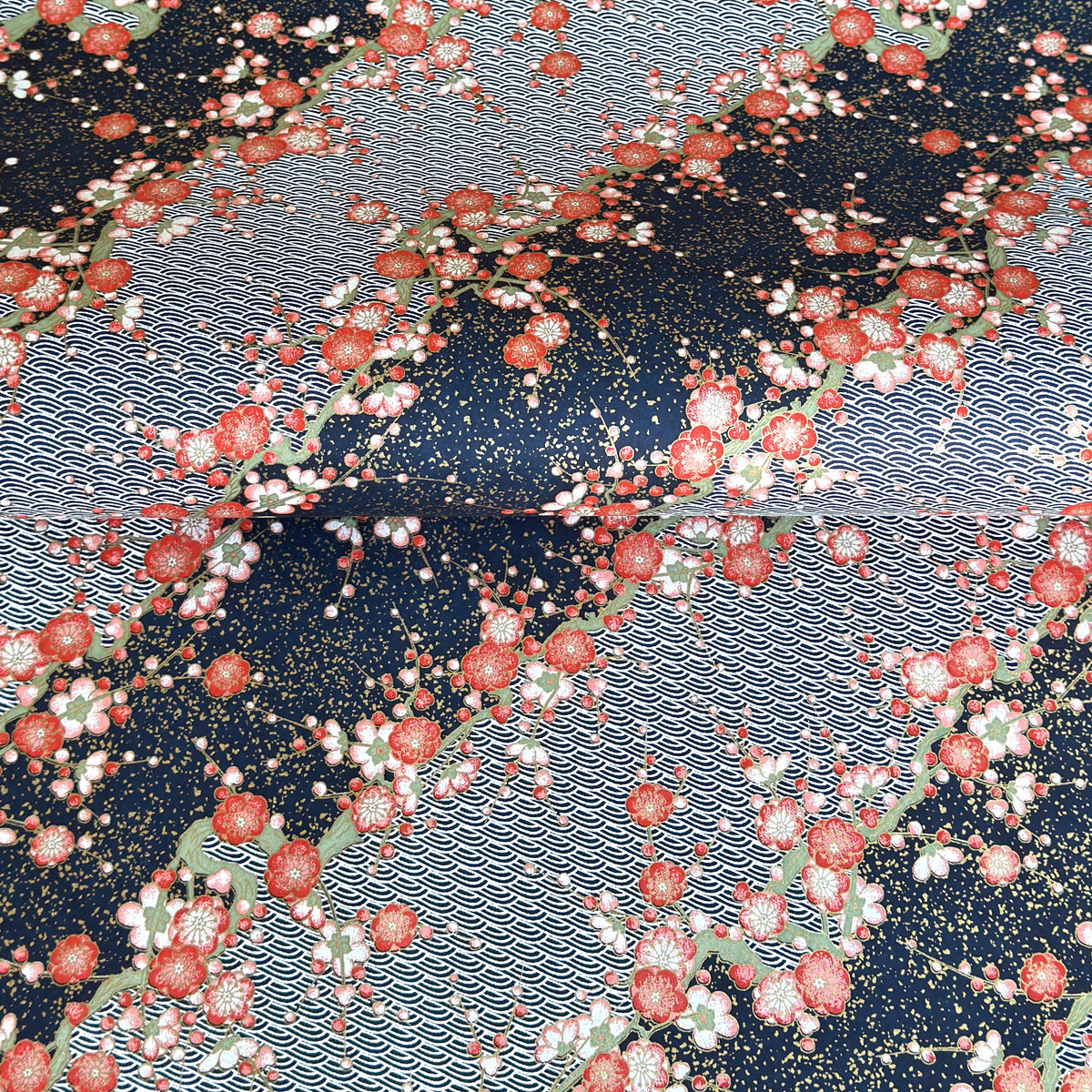 Diagonal branches of rich pink plum (ume) blossom on a midnight blue background with gold accents. Japanese chiyogami paper