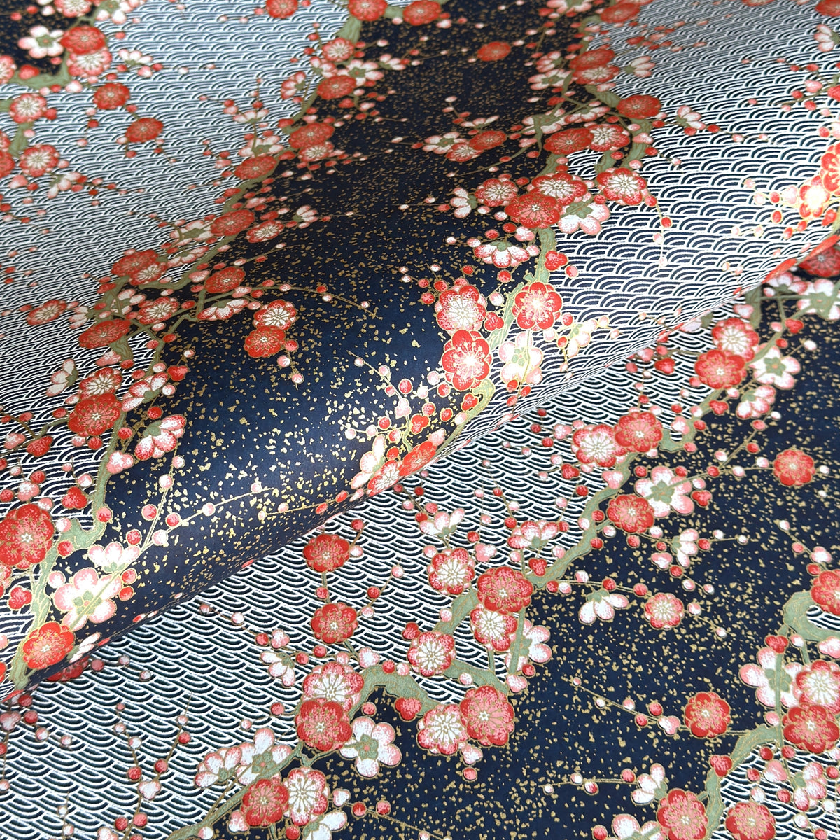 Diagonal branches of rich pink plum (ume) blossom on a midnight blue background with gold accents. Japanese chiyogami paper