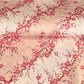 Diagonal branches of pink plum (ume) blossom on a light pink background with gold accents. Japanese chiyogami paper