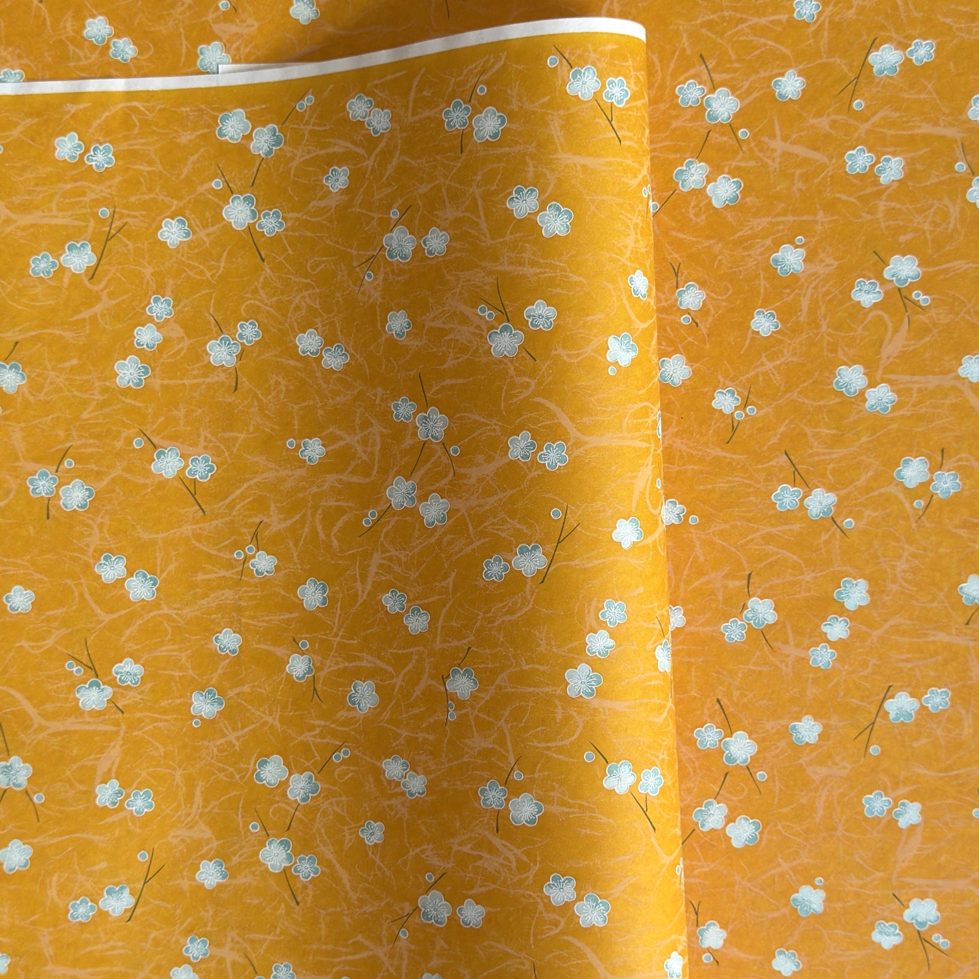 Pale blue plum (ume) blossom with a rich saffron backdrop.  Japanese chiyogami paper.