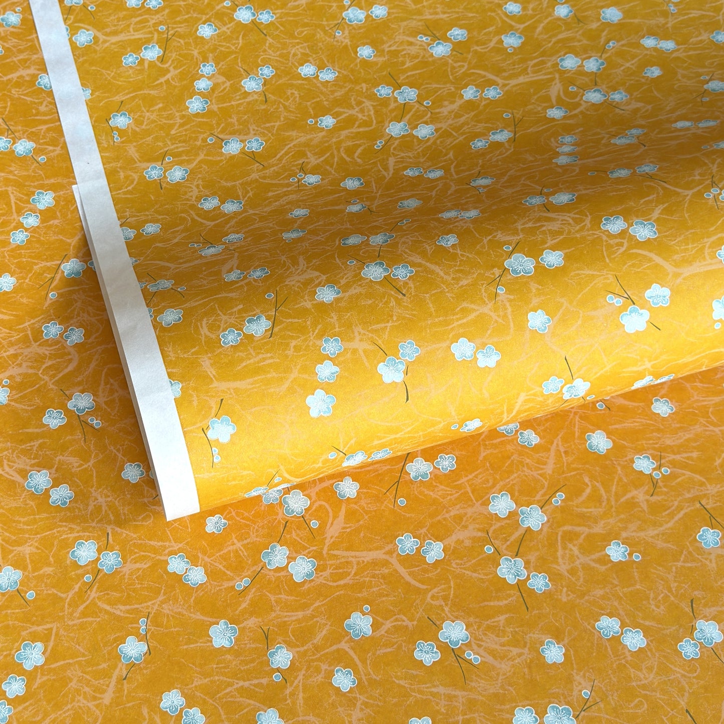 Pale blue plum (ume) blossom with a rich saffron backdrop.  Japanese chiyogami paper.