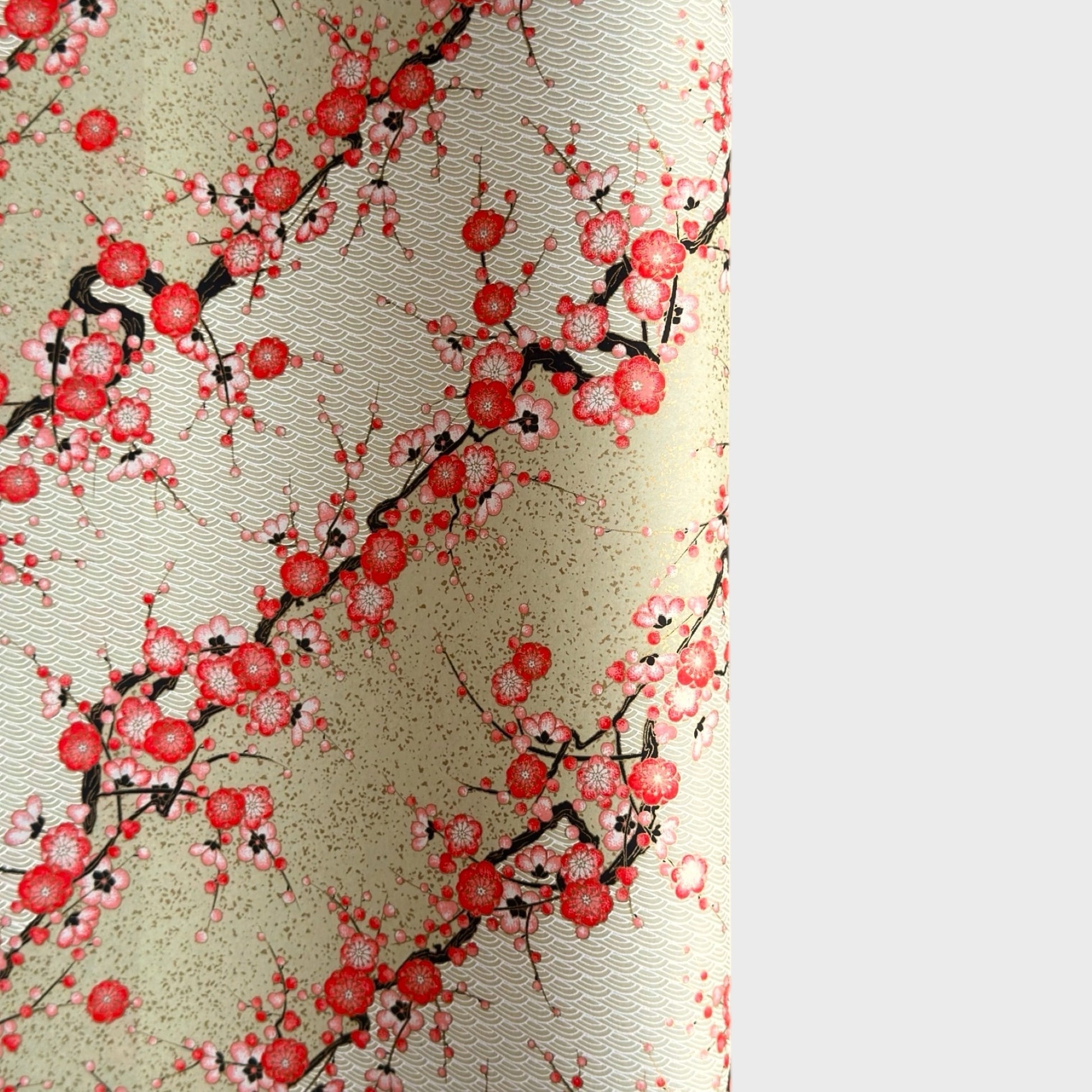 Japanese chiyogami silkscreen paper with diagonal branches of pink plum blossom on a sage green backdrop.