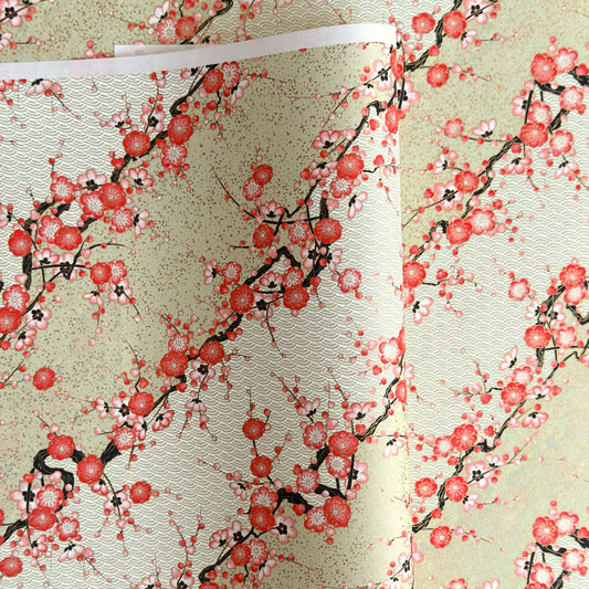 Japanese chiyogami silkscreen paper with diagonal branches of pink plum blossom on a sage green backdrop.