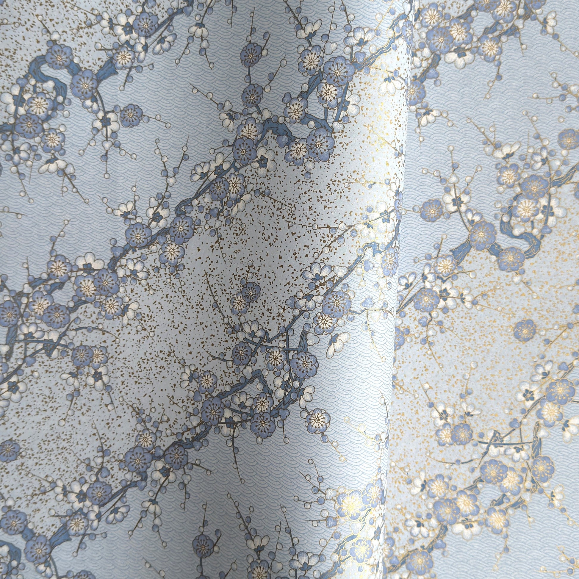 Japanese chiyogami paper with diagonal branches of sky blue plum blossom on a light blue background. 