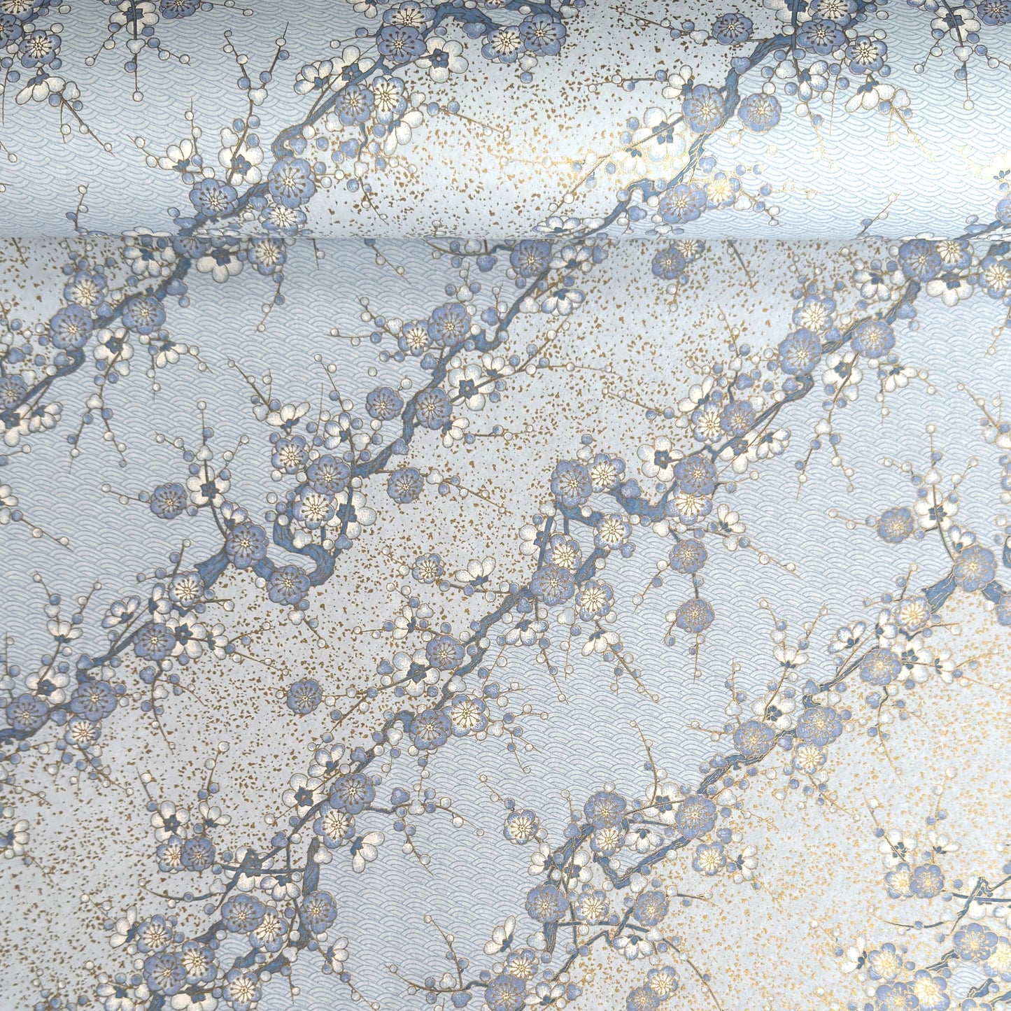 Japanese chiyogami paper with diagonal branches of sky blue plum blossom on a light blue background. 