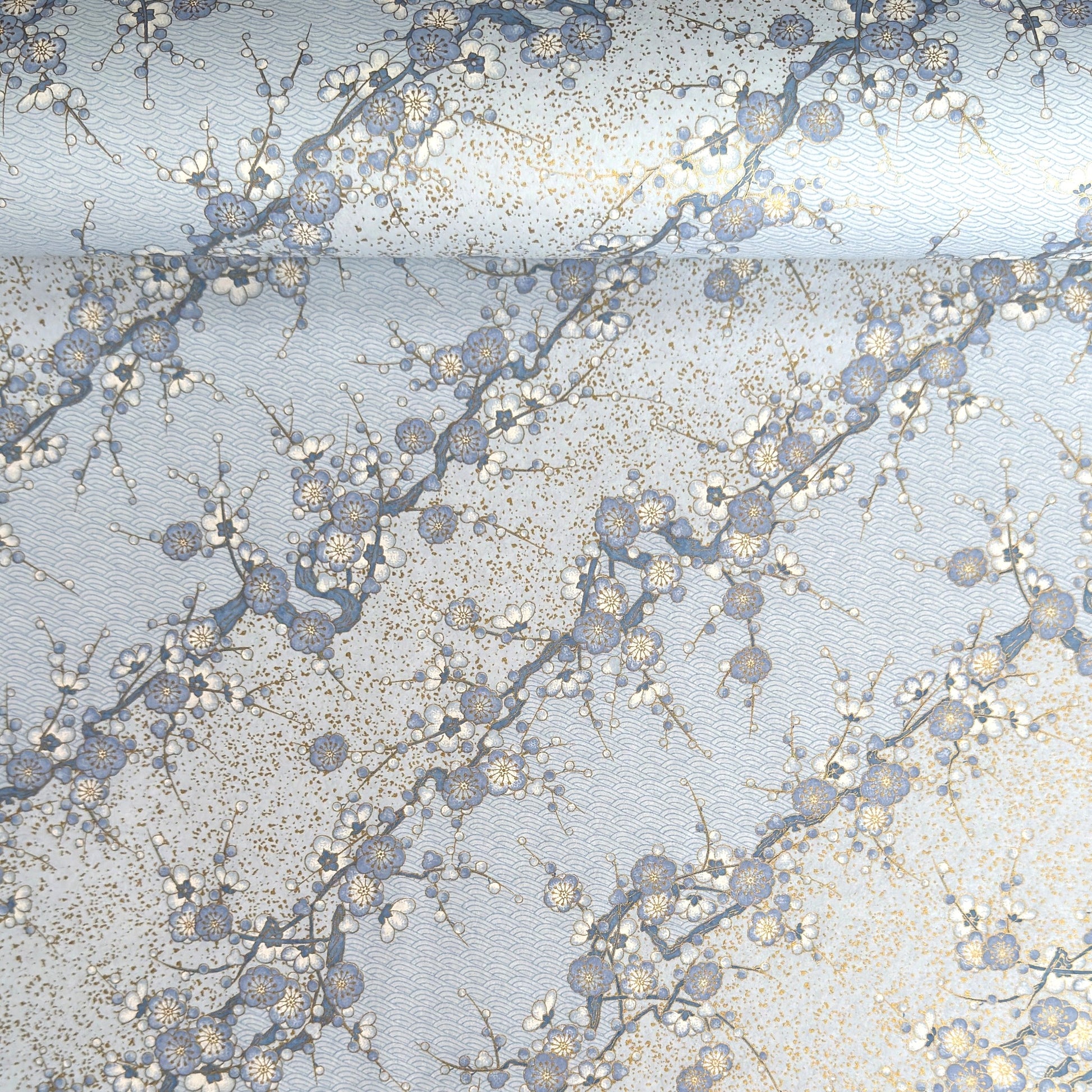 Japanese chiyogami paper with diagonal branches of sky blue plum blossom on a light blue background. 