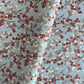 Japanese silkscreen chiyogami paper with a pattern of deep red, lilac and white plum blossom on a blue backdrop