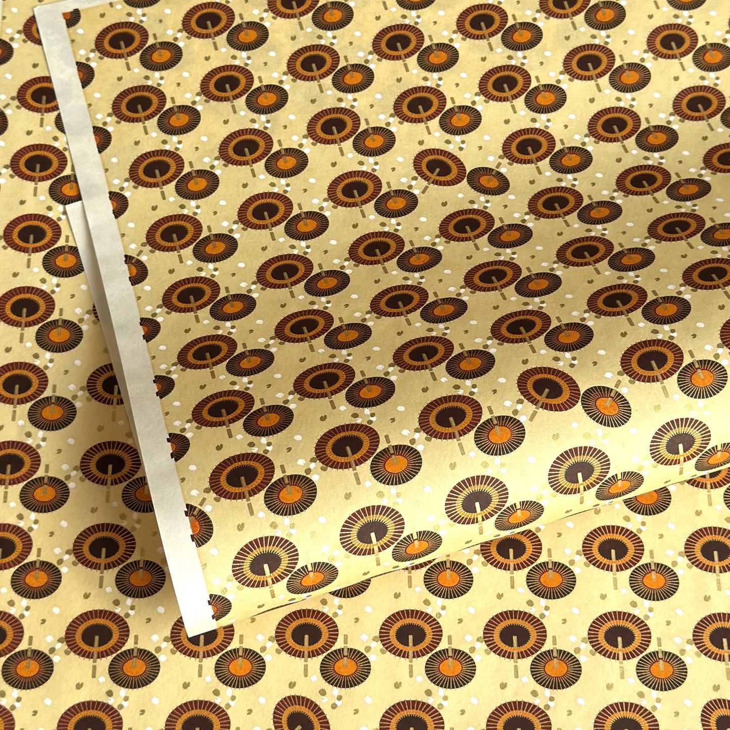 Japanese silkscreen chiyogami paper with a brown and orange umbrella pattern on a buttermilk backdrop 