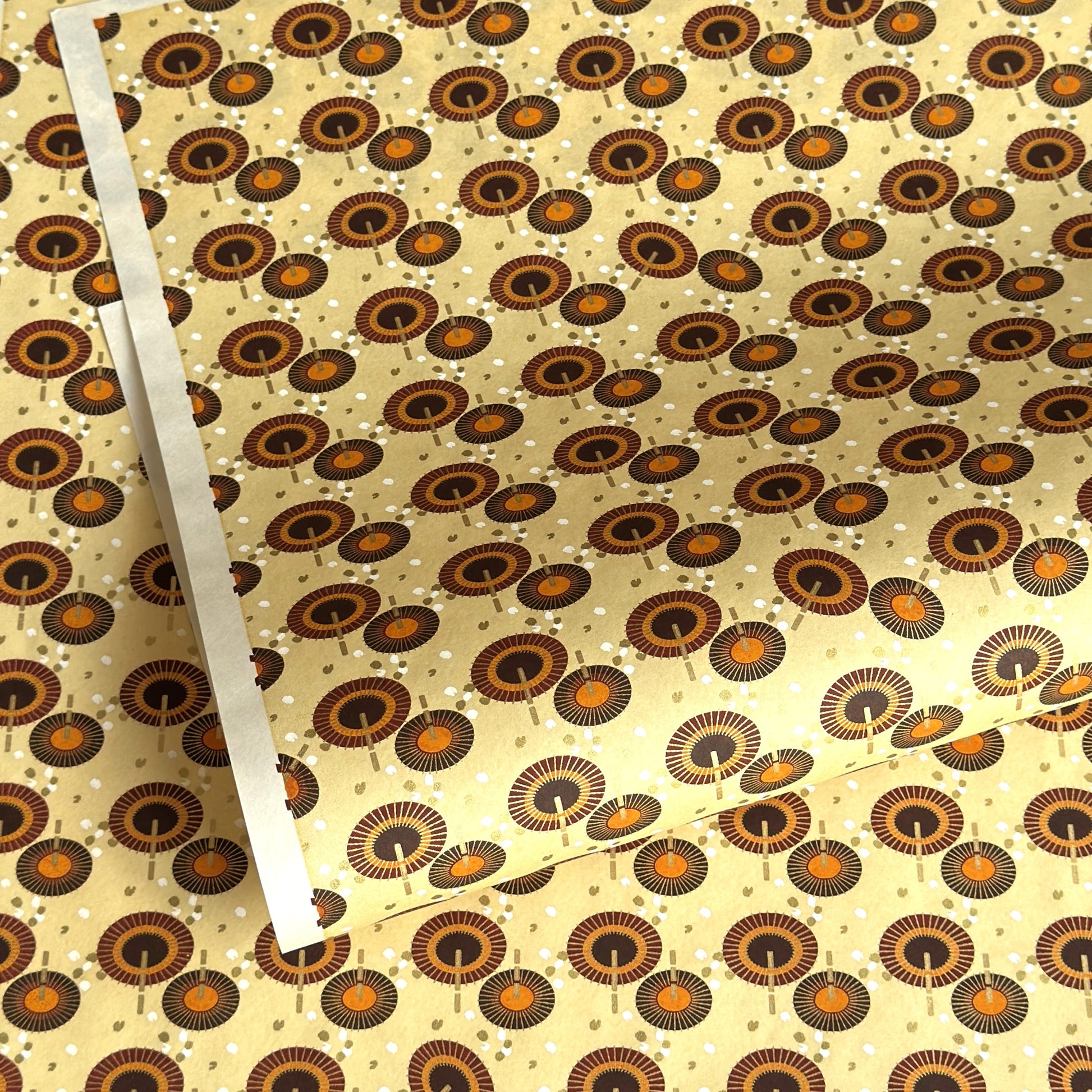 Japanese silkscreen chiyogami paper with a brown and orange umbrella pattern on a buttermilk backdrop 