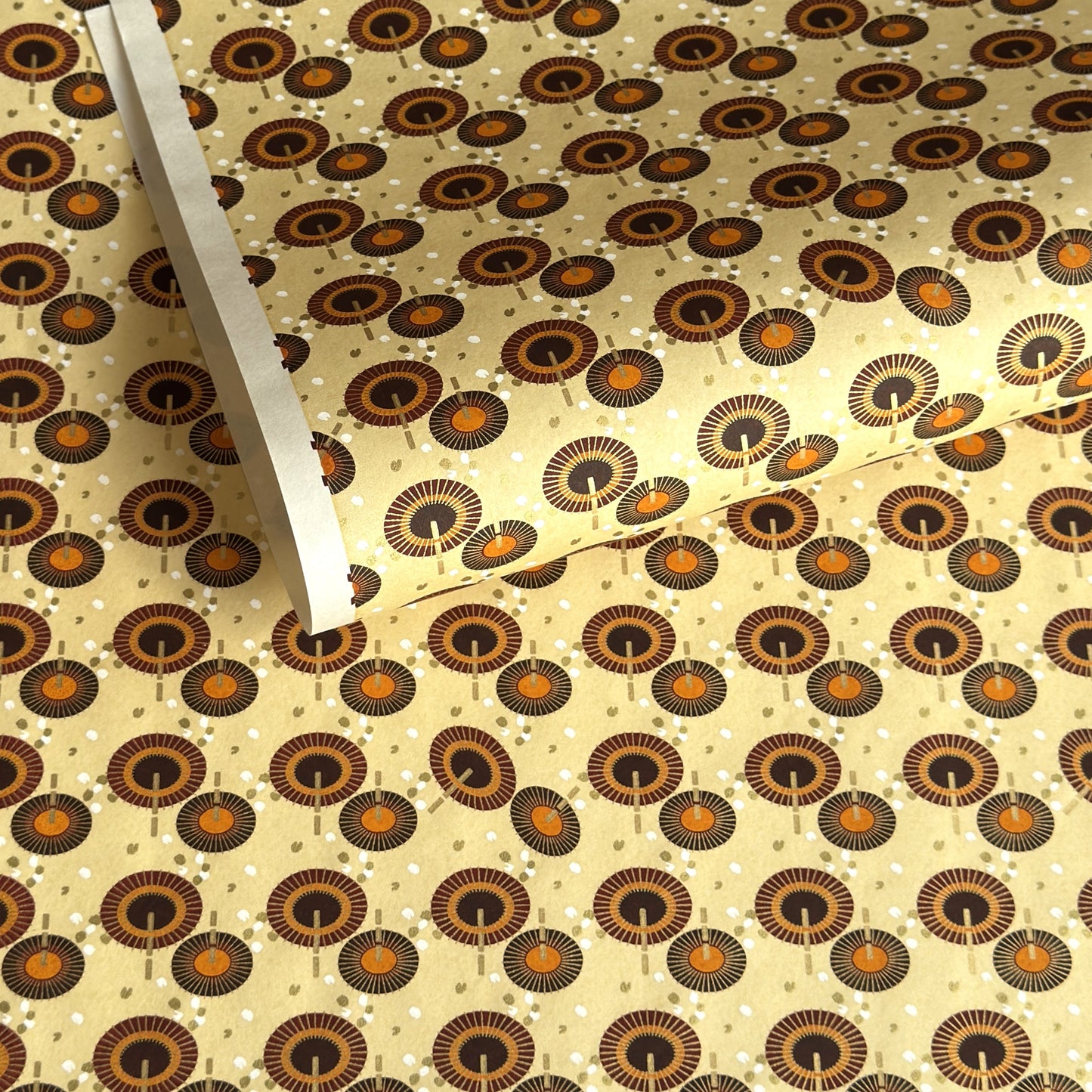 Japanese silkscreen chiyogami paper with a brown and orange umbrella pattern on a buttermilk backdrop 