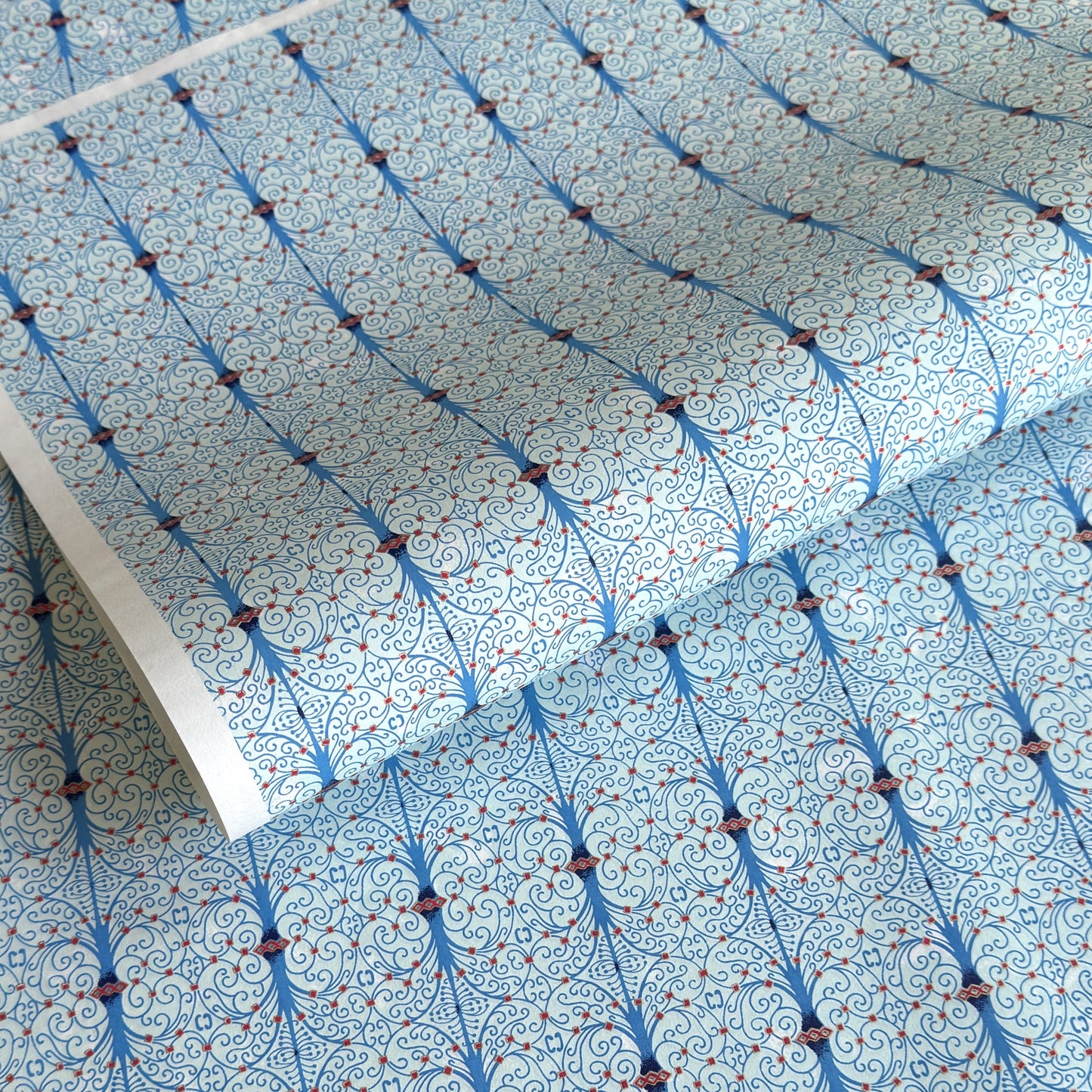 Japanese silkscreen chiyogami paper with a intricate filigree trellis design in blue with red and gold accent