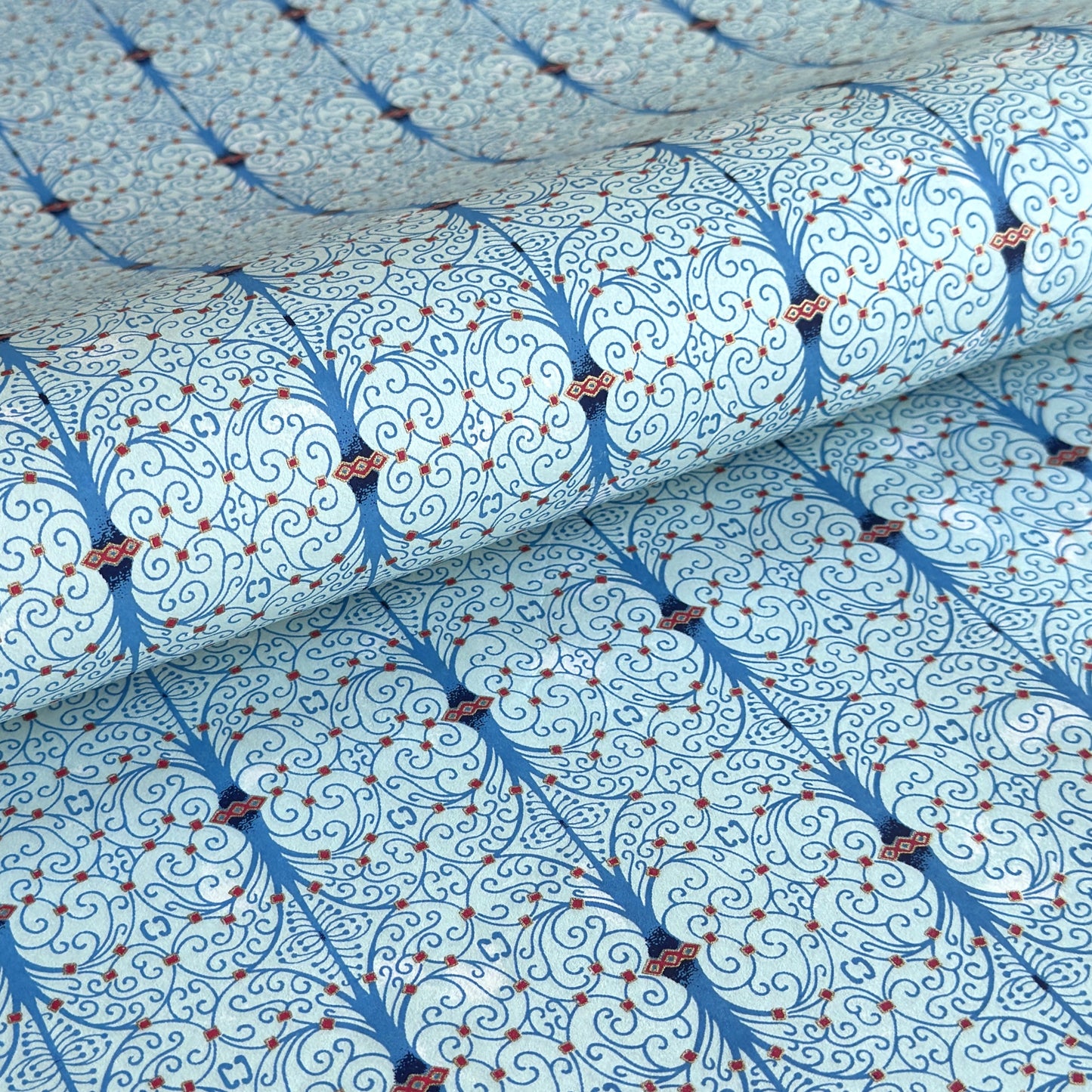 Japanese silkscreen chiyogami paper with a intricate filigree trellis design in blue with red and gold accent