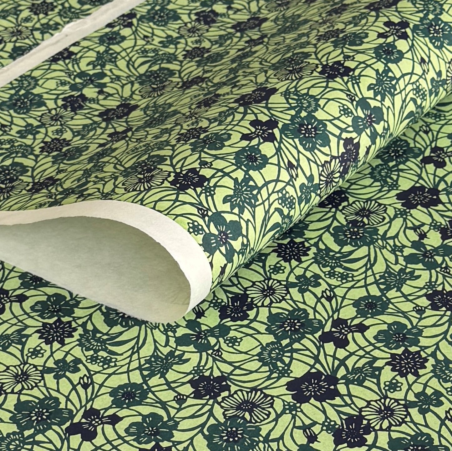 a sheet of katazome paper with a floral design in shades of green and indigo blue.