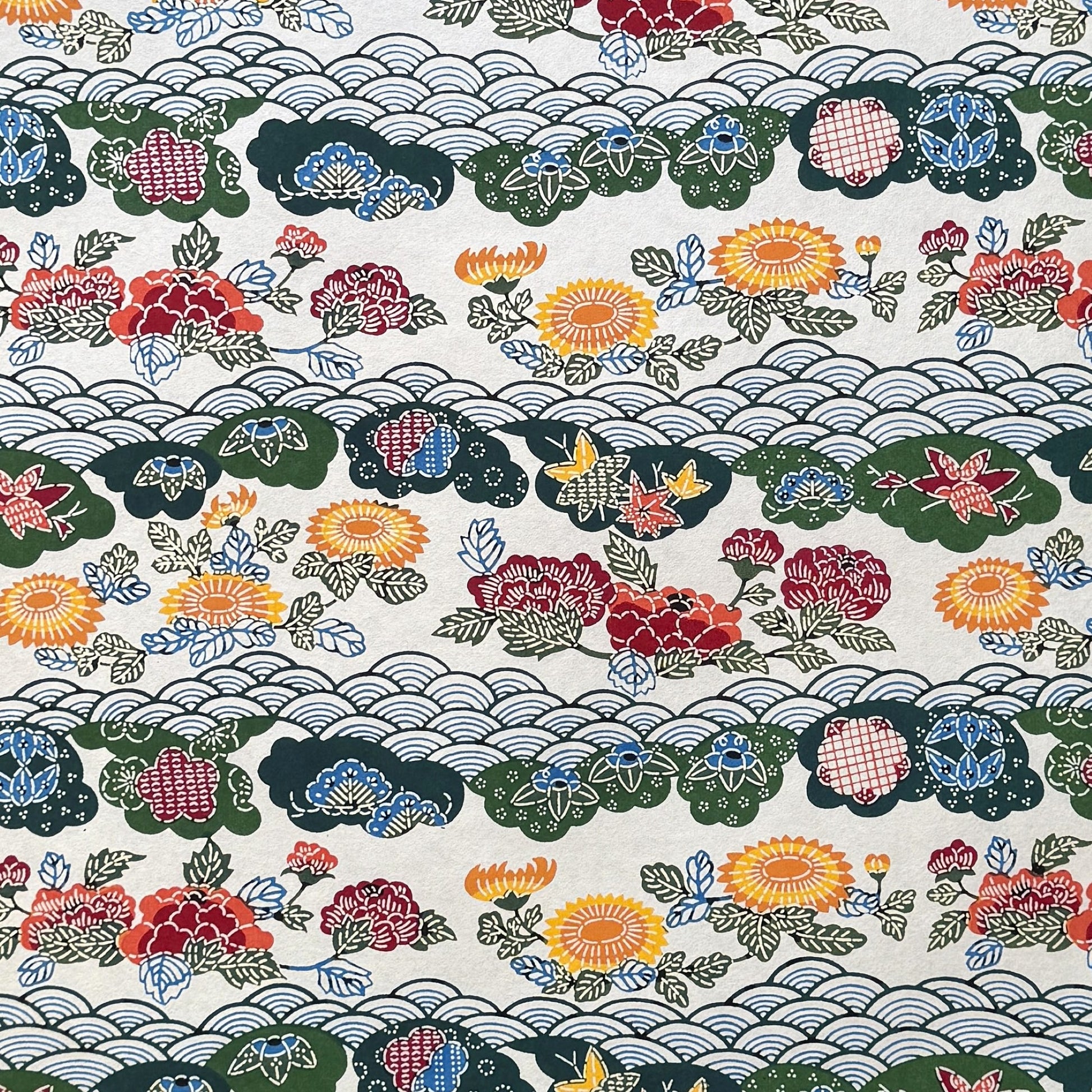 A colourful traditional pattern depicting stylised waves (seigaiha) with flowers and foliage in green, yellow, red and blue. A sheet of Japanese katazome paper.