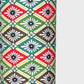 A sheet of katazome paper with a repeat rhombus pattern with the Japanese motif of the water caltrop plant (hishi) depicted alongside the four-petal flower of the water chestnut (hanabishi) in red, green. brown and teal.