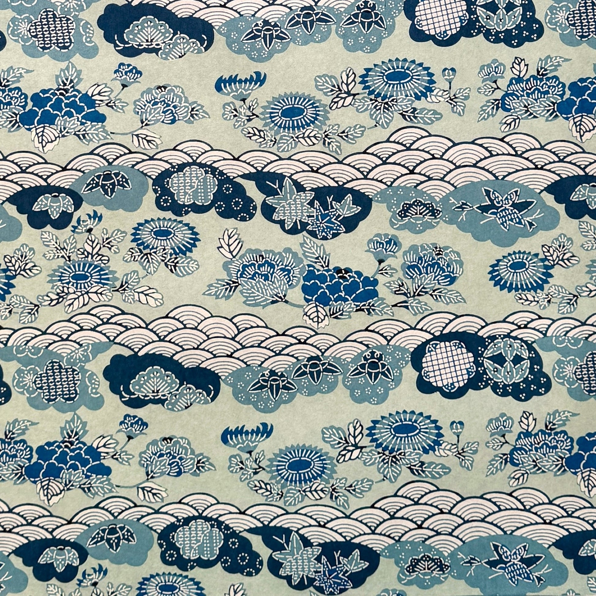 A colourful traditional pattern depicting stylised waves (seigaiha), flowers and foliage in a soft aqua and blue palette. A sheet of katazome paper