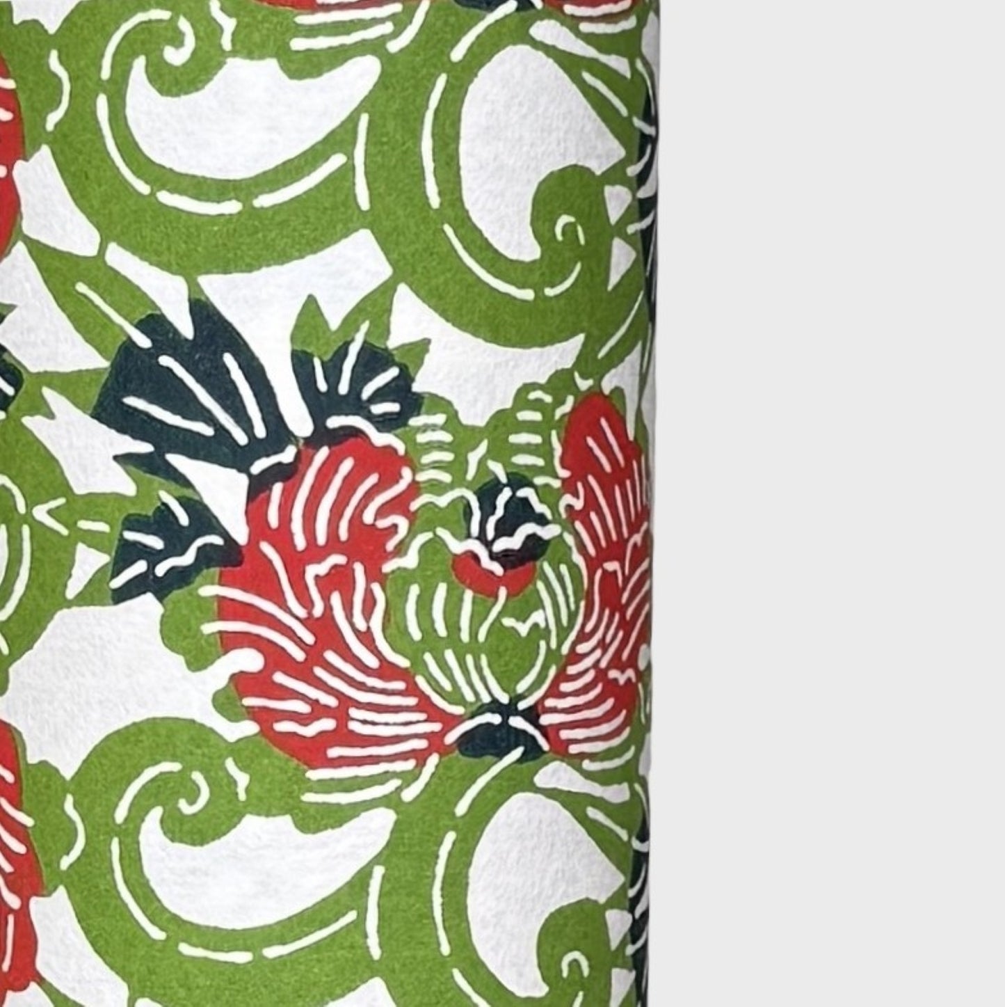 a sheet of katazome paper with a pattern of peonies (botan) in a rich red amongst green foliage. close up