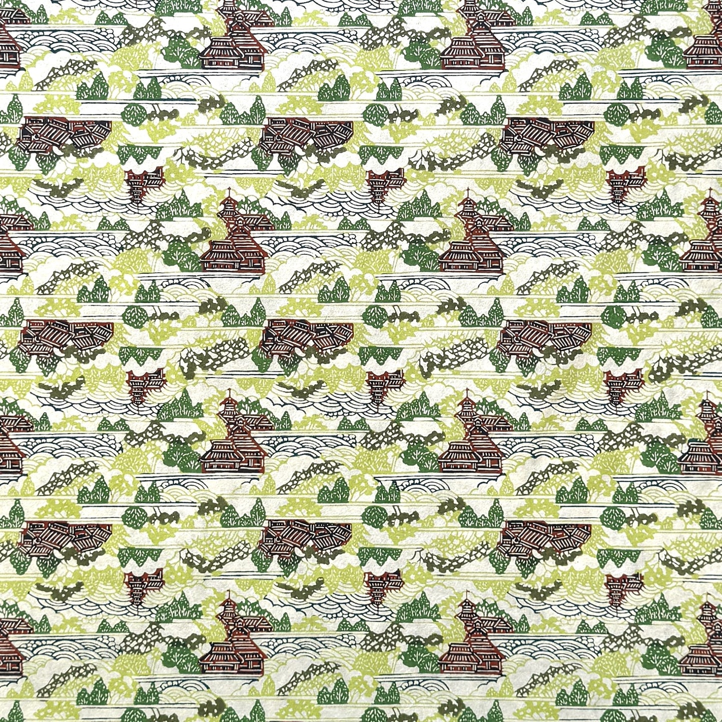 a sheet of katazome paper with a pattern of a hillside village in lime green, green and brown