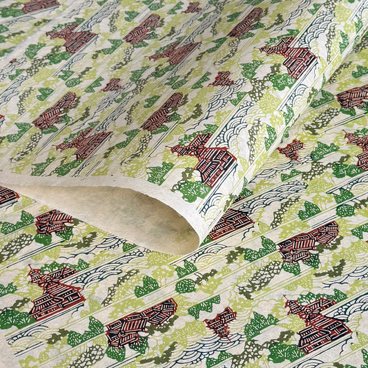 a sheet of katazome paper with a pattern of a hillside village in lime green, green and brown.