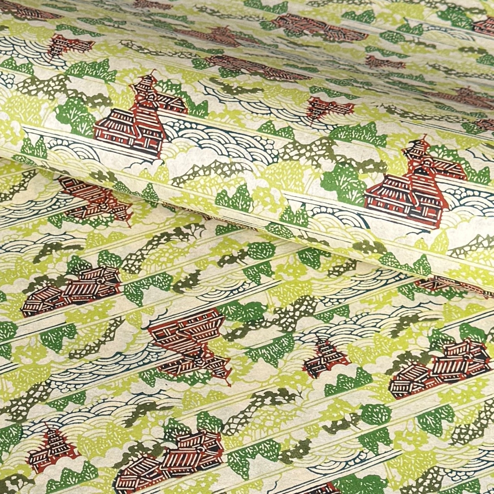a sheet of katazome paper with a pattern of a hillside village in lime green, green and brown