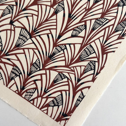 Japanese katazome-shi stencil-dyed paper with a fan-like pattern in deep maroon and black on cream paper. Close-up