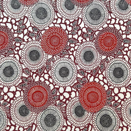 Japanese katazome-shi paper stencil-dyed with a pattern of stylised kiko flowers in red, maroon and black on an ivory paper.