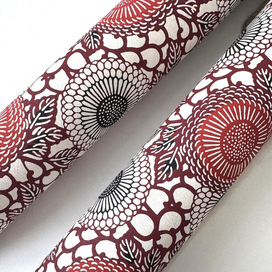 Japanese katazome-shi paper stencil-dyed with a pattern of stylised kiko flowers in red, maroon and black on an ivory paper.  Rolled