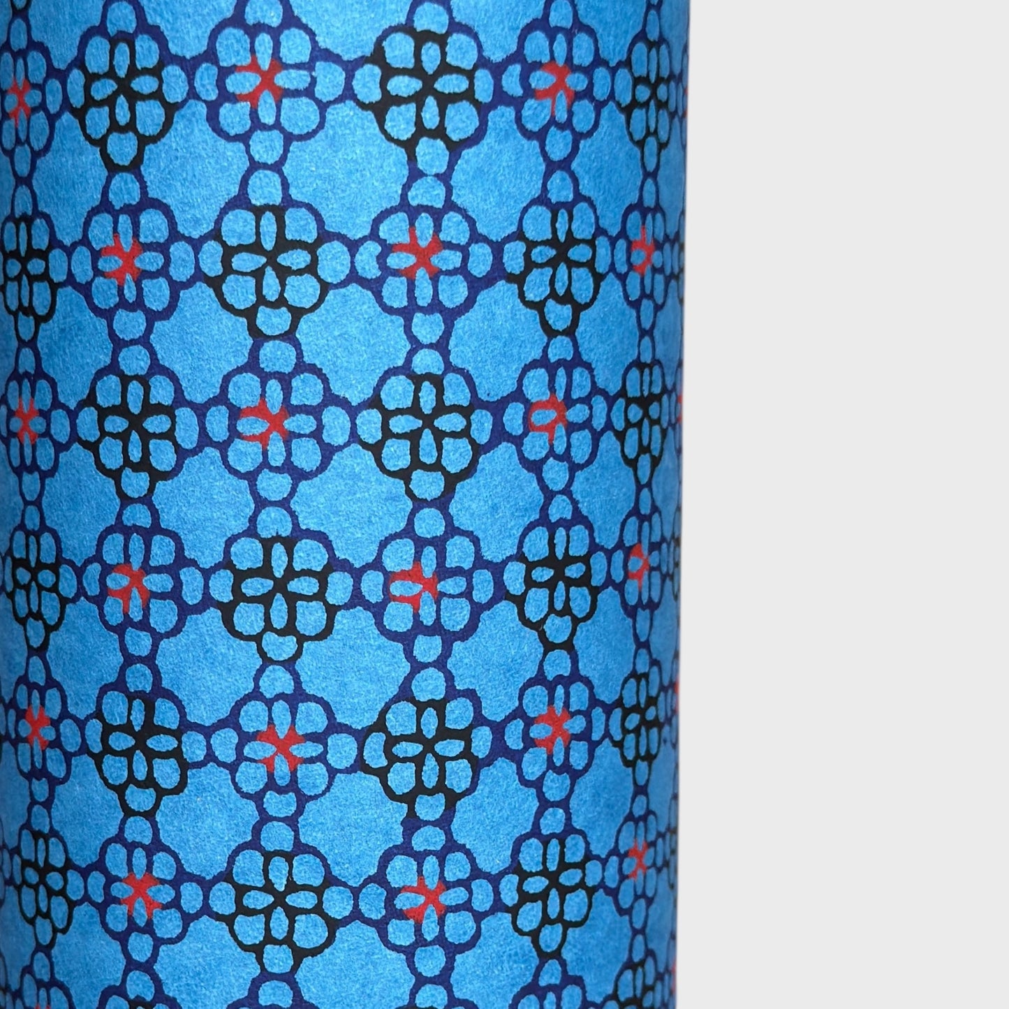 a sheet of Japanese katazome shi paper with a delicate tile repeat pattern on a bright blue backdrop. Close up