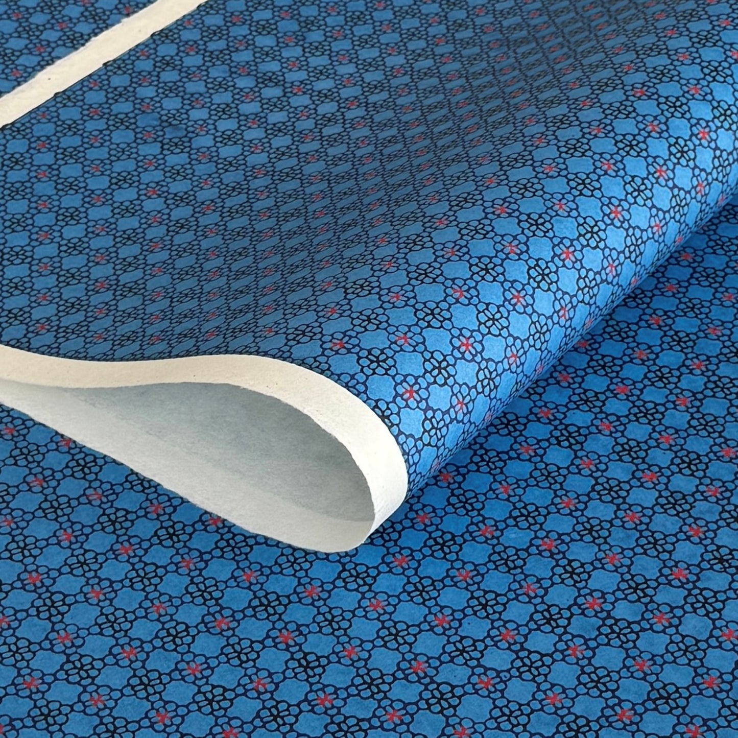 a sheet of Japanese katazome shi paper with a delicate tile repeat pattern on a bright blue backdrop