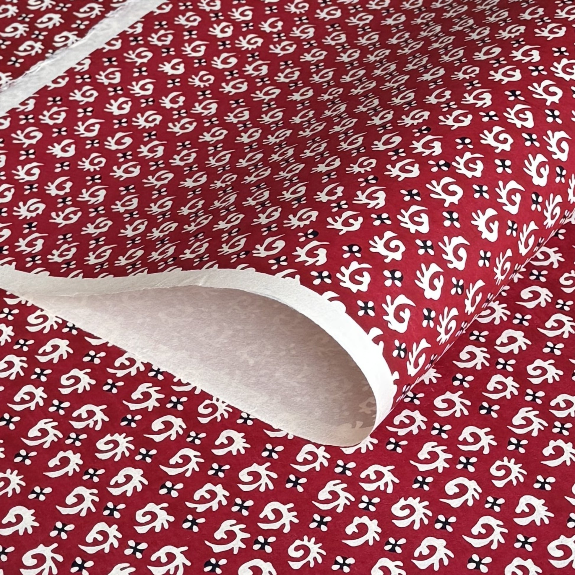 A Japanese stencil-dyed patterned paper with a repeat pattern in white on a deep rich red background.