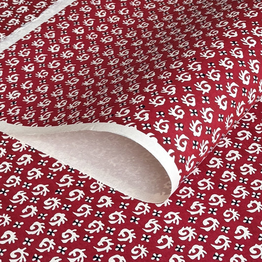A Japanese stencil-dyed patterned paper with a repeat pattern in white on a deep rich red background.