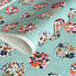 japanese stencil-dyed handmade paper with traditional botanical circles pattern on aqua backdrop