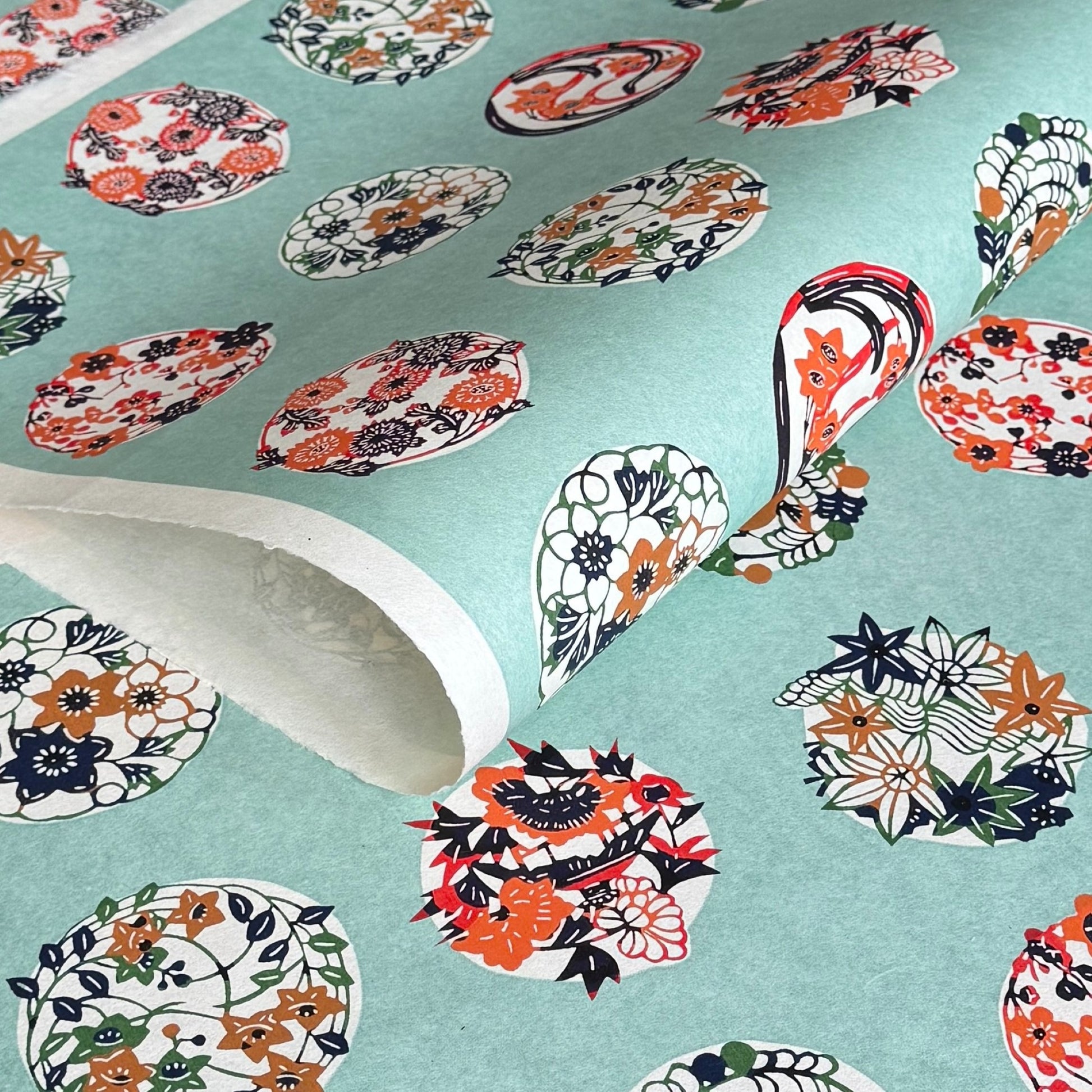 japanese stencil-dyed handmade paper with traditional botanical circles pattern on aqua backdrop