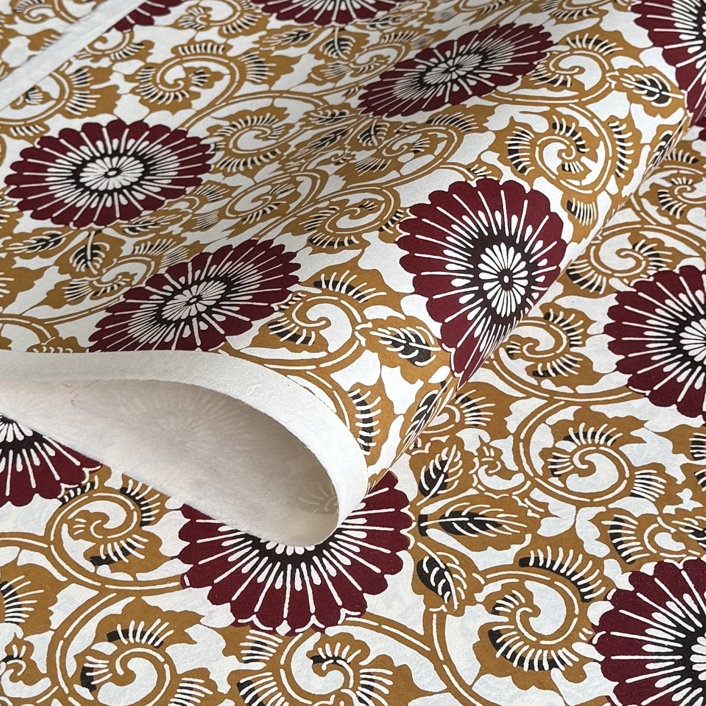 Japanese stencil-dyed paper with a large stylised floral pattern of a chrysanthemum in deep brown and tan.