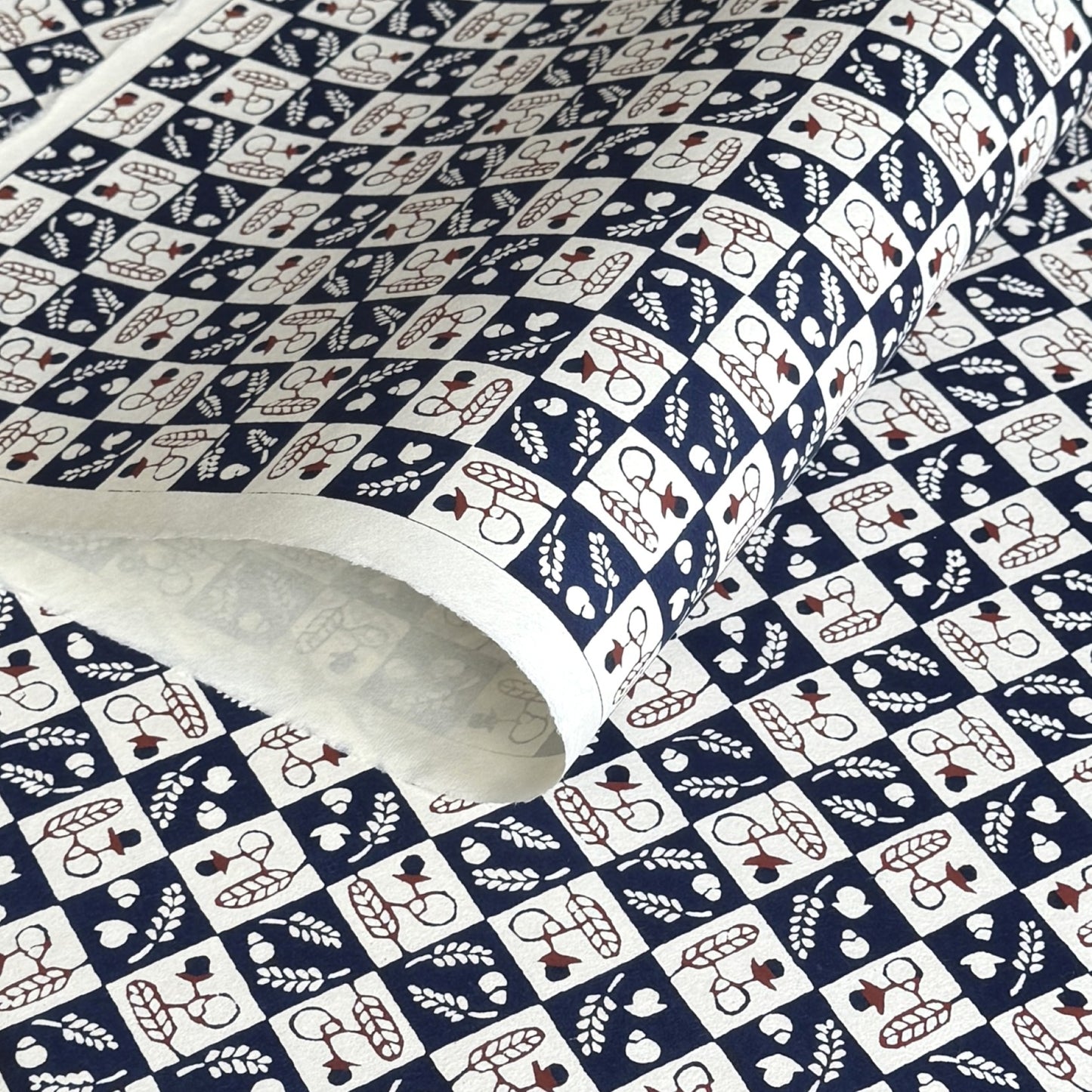 Japanese katazome-shi paper in navy blue and cream chequerboard pattern with motifs of autumn - acorns and wheat.
