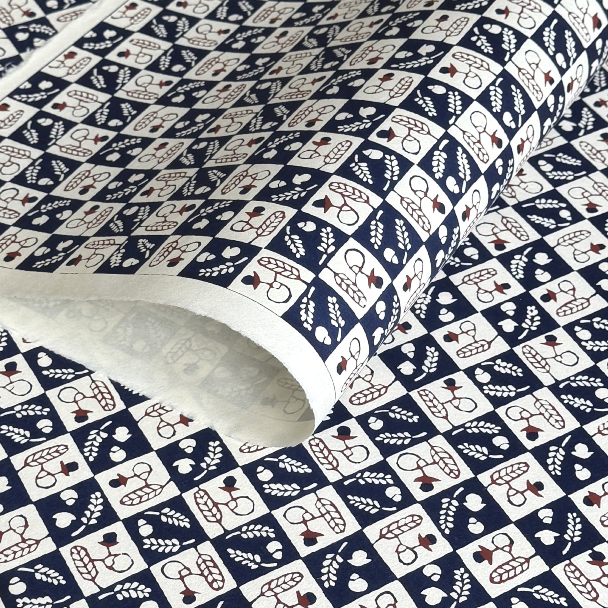 Japanese katazome-shi paper in navy blue and cream chequerboard pattern with motifs of autumn - acorns and wheat.